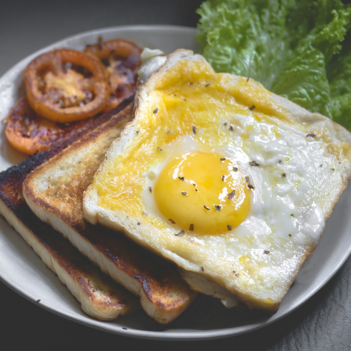 Brunch plate with baked egg in toast, roast tomato and salad